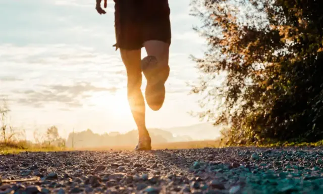 Gambe di un corridore su un sentiero sterrato al tramonto. Ottimo per bruciare calorie corsa 7 km/h.