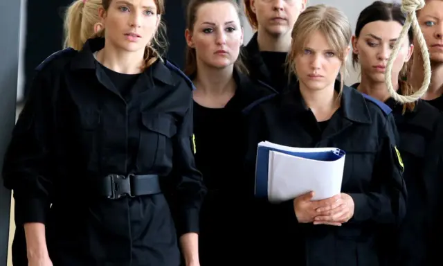 Grupa niebezpieczne kobiety w czarnych mundurach, jedna z nich trzyma teczkę, w tle sznur.
