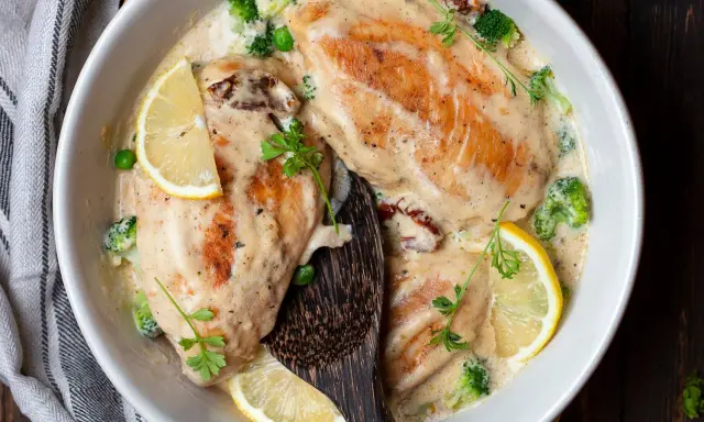 Deliziose scaloppine al vino bianco in una cremosa salsa, guarnite con limone, broccoli e piselli. Un piatto invitante e saporito.
