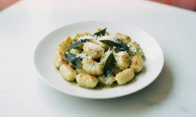 Pyszne gnocchi z sosem, posypane parmezanem i ozdobione listkami szałwii. Idealne danie dla miłośników włoskiej kuchni.