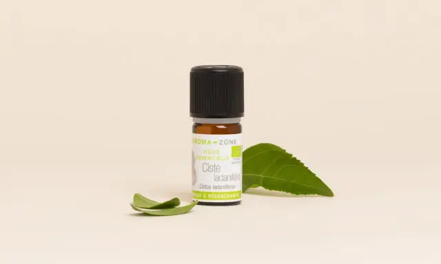 Flacon d'huile essentielle de ciste, aux vertus uniques et régénérantes, accompagné de feuilles vertes.