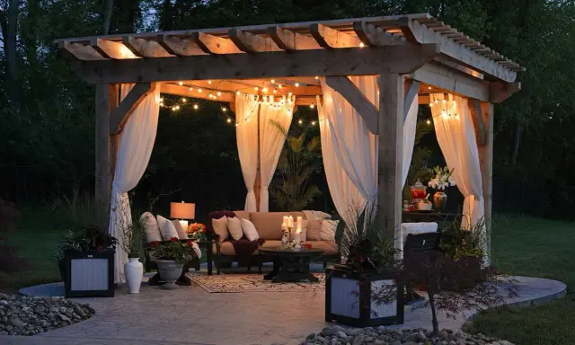 Mysig uteplats med draperade gardiner och ljusslingor. Perfekt liten uteplats inspiration för sommarkvällar.