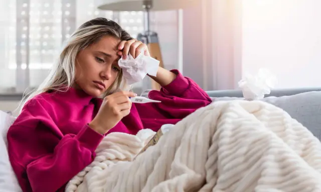Donna malata con termometro e fazzoletto, preoccupata per il suo stato, forse **immunodepresso significato** da approfondire.