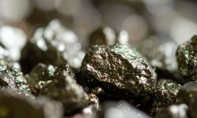Zbliżenie na błyszczące bryłki pirytu, ukazujące jego metaliczny połysk i nierówną powierzchnię. Piryt właściwości tego minerału fascynują.
