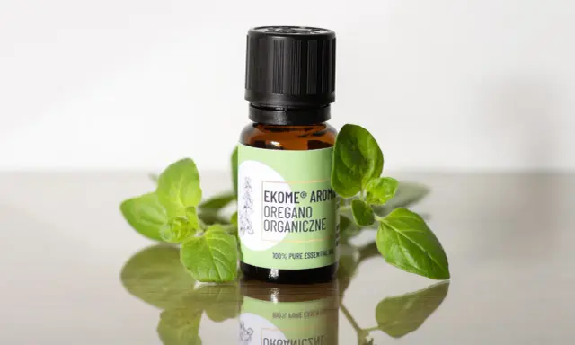 Szukasz, gdzie kupić olejek z oregano? Na zdjęciu buteleczka z organicznym olejkiem z oregano, otoczona świeżymi gałązkami.