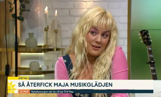 Maja Francis, med sitt blonda hår och rosa tröja, pratar om hur hon återfick sin musikglädje. En gitarr syns i bakgrunden.
