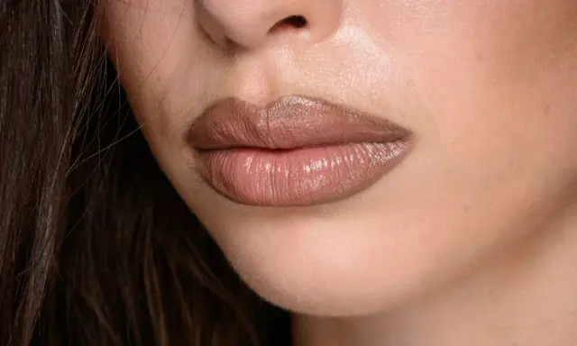 Labbra carnose e lucide, con un effetto naturale per ingrandire le labbra, evidenziate da un rossetto nude.