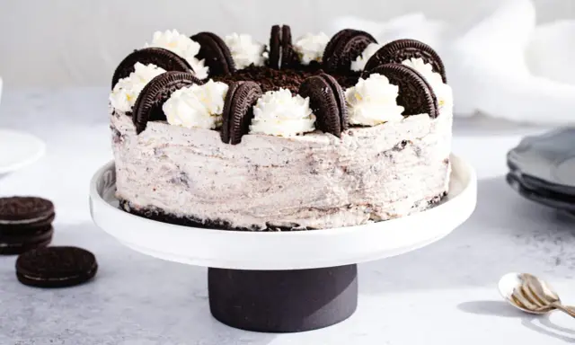 Pyszny sernik oreo na zimno, udekorowany bitą śmietaną i ciasteczkami. Idealny deser na upalne dni.