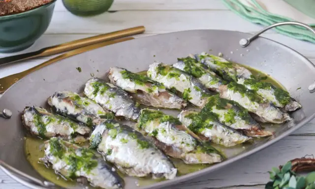Deliciosas sardinas al horno, cubiertas con una sabrosa salsa verde, listas para disfrutar.