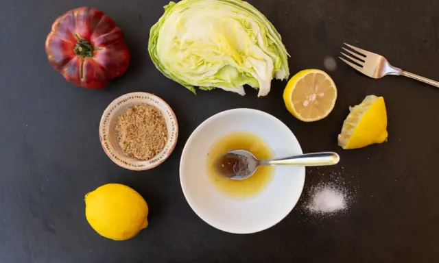 Zutaten für ein einfaches salatdressing mit zitrone und zucker: Eisbergsalat, Tomate, Zitronen, brauner Zucker und Salz.