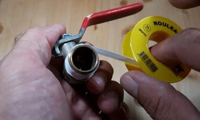 Main tenant une vanne, il applique du ruban de téflon pour assurer une étanchéité parfaite.