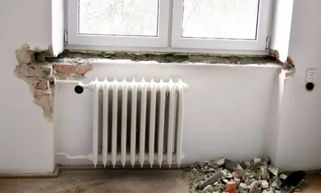 Rozpoczęła się wymiana parapetu wewnętrznego. Widać gruz pod oknem i odsłoniętą cegłę.