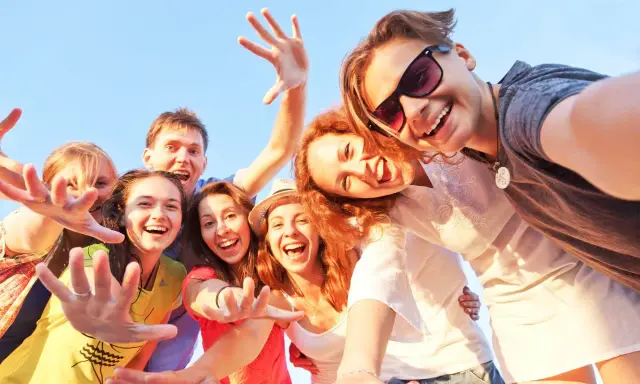 Uśmiechnięta grupa przyjaciół robi selfie. Ich radość i bliskość to czynniki chroniące przed samotnością.