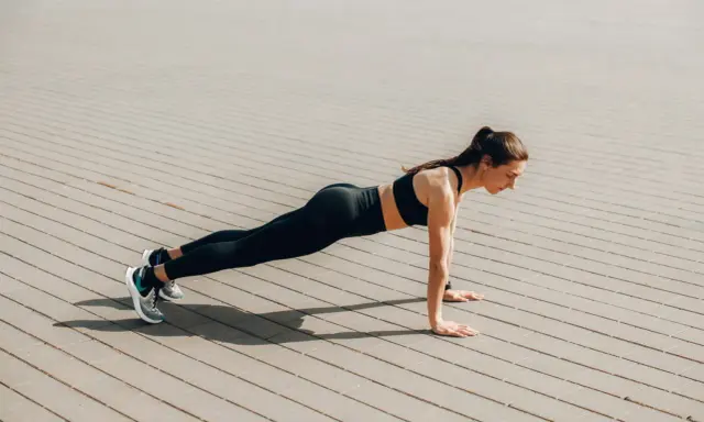 Femme en tenue de sport faisant une planche, un excellent exercice pour perdre du ventre.