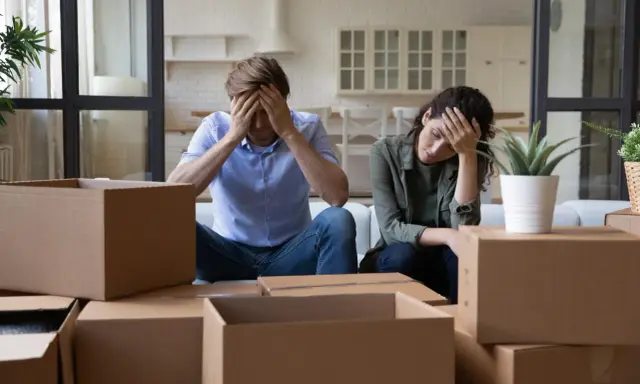 Couple overwhelmed by the stress of moving, surrounded by moving boxes.
