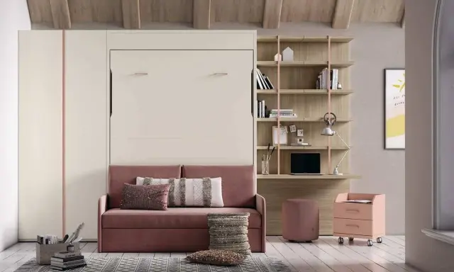 Sofá rosa con cojines, junto a una estantería y una **cama nido vertical** oculta.