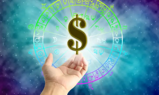 Znak dolara unosi się nad dłonią na tle koła zodiaku. Czy to zapowiedź sukcesu w pracy dla Ryb?
