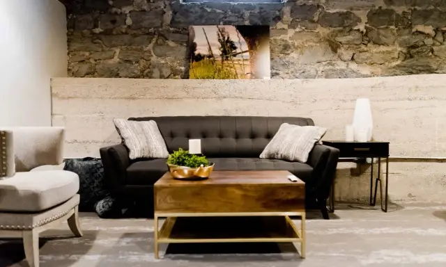 Gemütliches Wohnzimmer im industrial style mit dunklem Sofa, Holztisch und Steinwand.