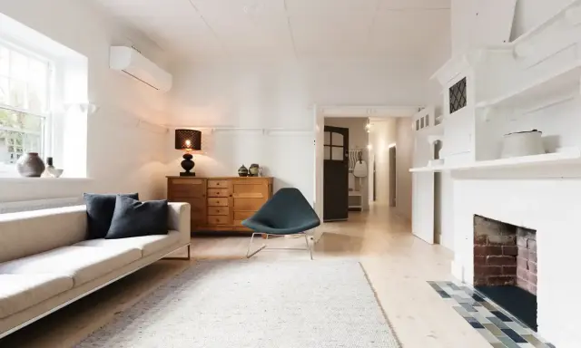 Salon lumineux avec canapé, fauteuil, buffet en bois et cheminée. Idéal pour savoir comment trouver un appartement rapidement.