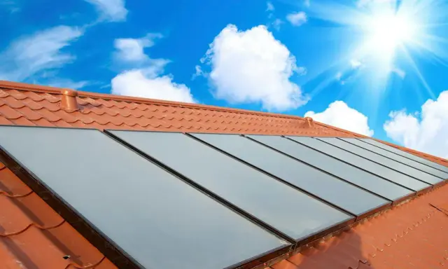 Fakta om solceller: Solpaneler på ett tegeltak fångar solens energi under en klarblå himmel med moln.