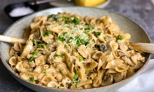En krämig kyckling svamp pasta i en skål, toppad med persilja och parmesan.