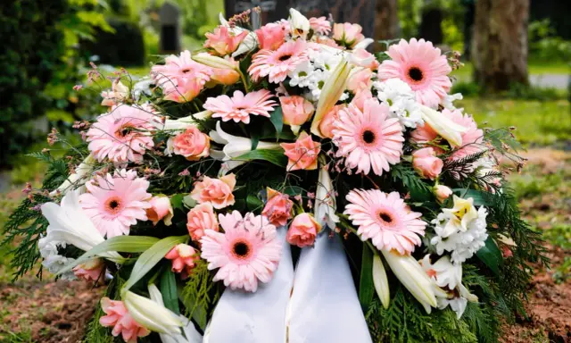 Wieniec pogrzebowy z różowymi gerberami i różami. Szarfy z wieńców można wykorzystać do ozdoby grobu lub jako materiał do rękodzieła.