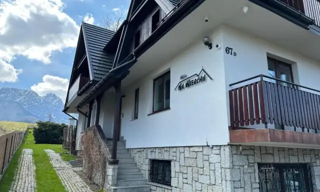 Willa Na Wierchu w Zakopanem, z kamienną podmurówką i drewnianymi elementami, wita gości pod malowniczymi Tatrami.
