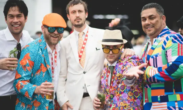 Men at the Kentucky Derby sport vibrant, patterned suits, showcasing bold fashion choices.