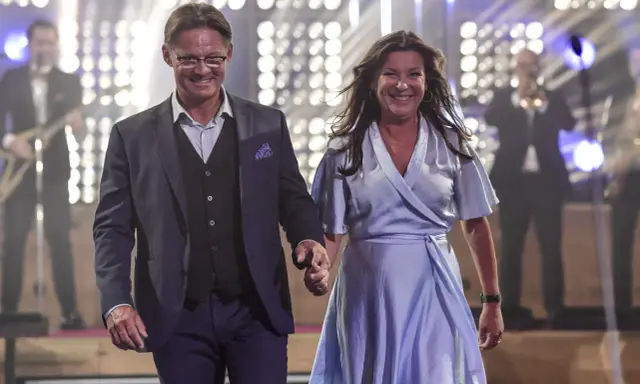 Lotta Engberg och ett leende raffset på scenen, med ett band i bakgrunden.