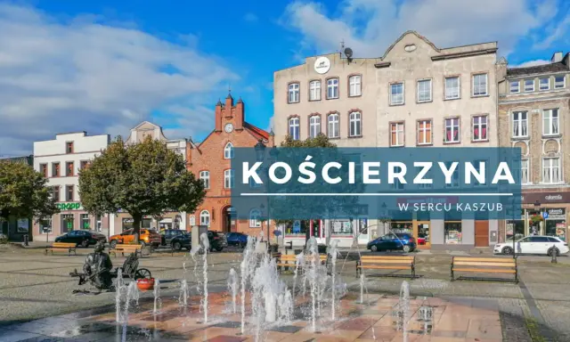 Kościerzyna rynek z fontanną i ławkami, otoczony kamienicami.