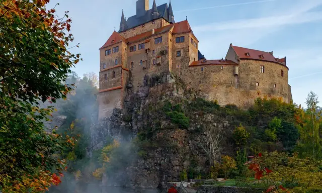 Zamek na skale nad wodospadem, jesienne liście i mgła tworzą malowniczy krajobraz. Wspaniałe wschodnie Niemcy atrakcje.
