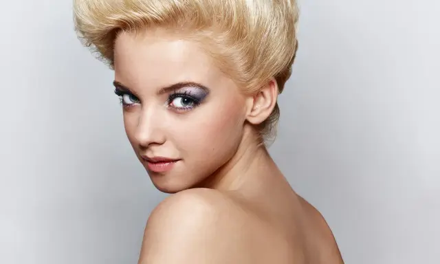 Mujer joven con peinado voluminoso y maquillaje llamativo, sus ojos de bambi cautivan la mirada.