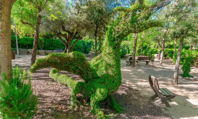 Un dragón de topiaria verde en un parque. Un lugar genial donde ver animales en Madrid, aunque este sea de plantas.