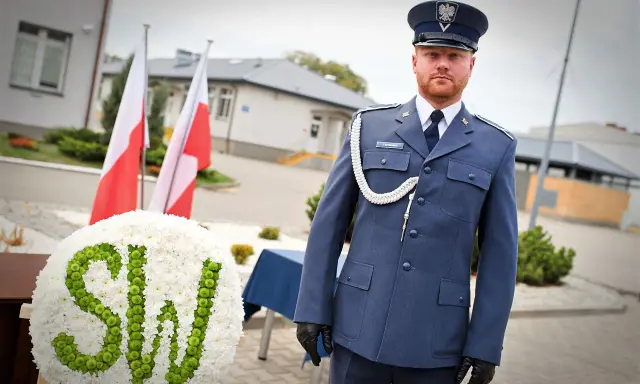 Mężczyzna w mundurze galowym SW, biało-zielony wieniec z napisem SW, polskie flagi.