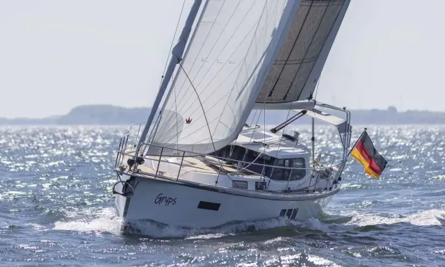 Le voilier Sirius 40 DS "Gryps" navigue sur une mer scintillante, pavillon allemand au vent.