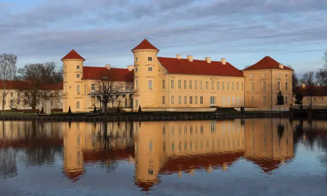 Das Schloss Rheinsberg spiegelt sich im Wasser. Die historische Altstadt von Rheinsberg zeigt sich von ihrer schönsten Seite.
