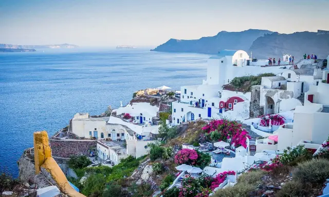 Białe domy na zboczu klifu z widokiem na morze, Santorini, Grecja.