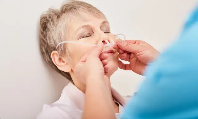 Ältere Frau mit Nasenbrille zur Sauerstofftherapie, ein Zeichen des COPD-Krankheitsbildes.