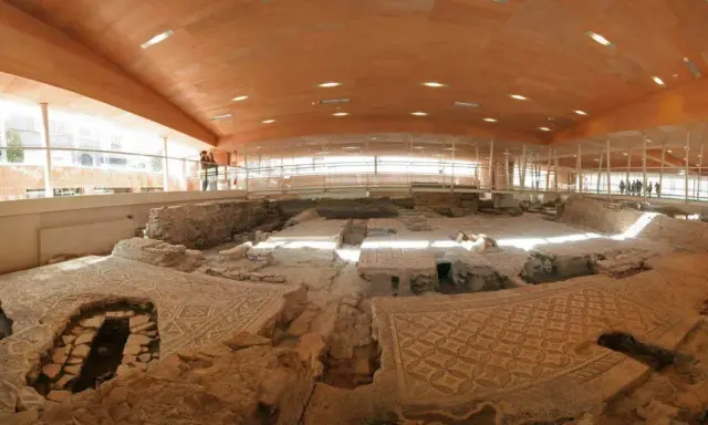Resti archeologici della domus del chirurgo, con pavimenti a mosaico ben conservati sotto una moderna copertura in legno e vetro.
