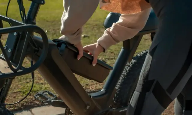 Osoba wyjmuje baterię z roweru elektrycznego, przygotowując się do ładowania.