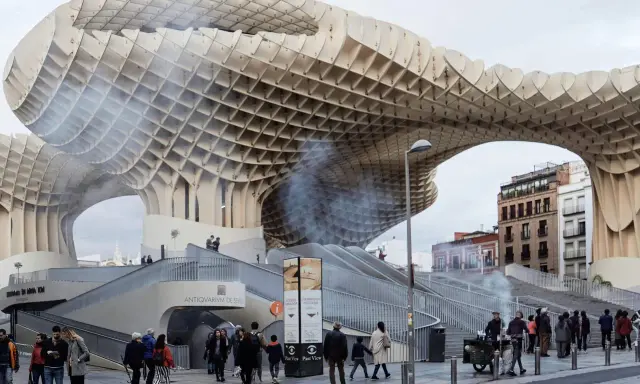 Ein Meisterwerk des Dekonstruktivismus: die Metropol Parasol in Sevilla. Menschen schlendern unter der organisch geformten Holzkonstruktion hindurch.