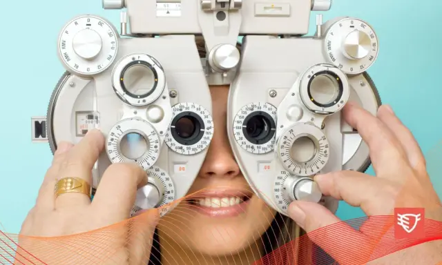 Badanie optometryczne: pacjent uśmiecha się, gdy optometrysta reguluje soczewki refraktora.