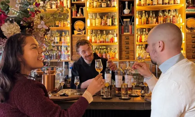 Två personer njuter av en ölprovning i Stockholm. En glad bartender serverar.