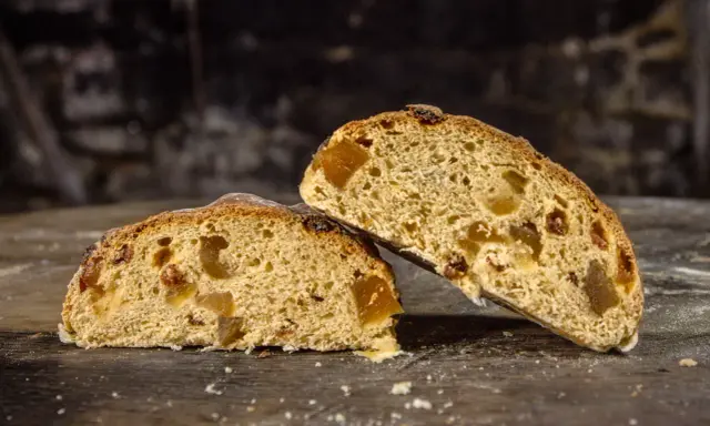 Deux tranches de pain au levain de gingembre, garnies de fruits confits, sur une table en bois rustique.