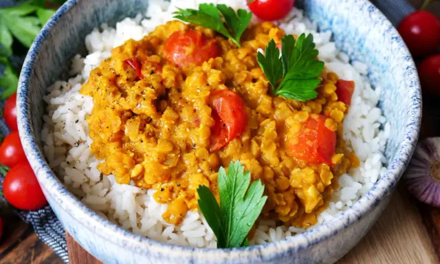 Herzhaftes rote Linsen Curry mit Reis, garniert mit frischer Petersilie und Kirschtomaten. Ein Genuss für die Sinne!