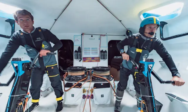 Deux marins concentrés sur le pont d'un bateau, prêts pour la course **Kerkena 6.1**.