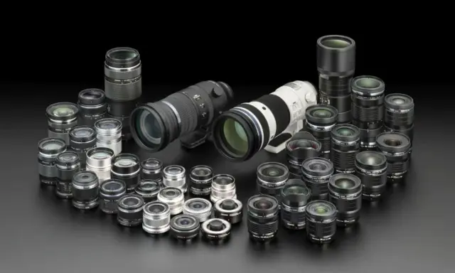 Collezione di obiettivi fotografici di varie dimensioni, dai teleobiettivi ai grandangolari, disposti su sfondo nero. Un vero tesoro per ogni appassionato di termini fotografici.