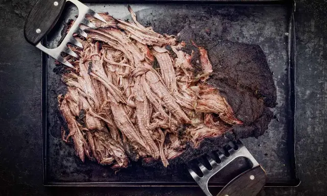 Zartes pulled beef, frisch aus dem Dutch Oven, wird mit Fleischkrallen zerteilt. Perfekt für BBQ!