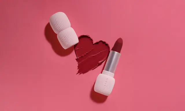 Un cuore di rossetto rosso, con un rossetto e un applicatore, mostra diversi tipi di rossetto.