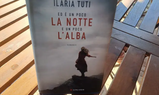 Copertina del libro "Ed è un poco la notte e un poco l'alba" di Ilaria Tuti, con una figura femminile su uno sfondo nebbioso.